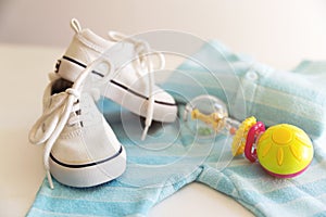 Baby stuff is on a white background. Things for little boy, rattle and shoes. Newborn baby necessities. photo