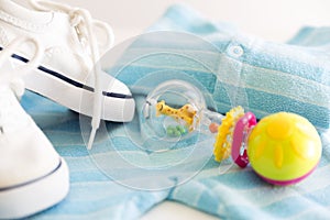 Baby stuff is on a white background. Things for little boy, rattle and shoes. Newborn baby necessities. photo