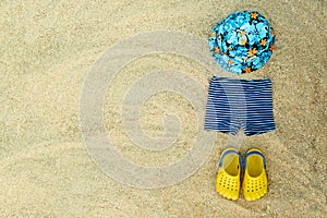 Baby summer beachwear, flip flops, hat, shorts on sand beach