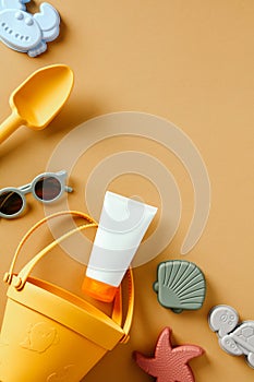 Baby Sunscreen with beach toys on sand color background. Sun cream design. Flat lay. Top view