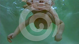 Baby swimming. Learning to swim a child under 1 year. Diving an infant in the bathroom under the supervision of a doctor, trainer