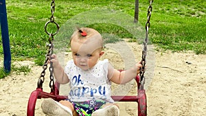 baby swinging on a swing on a clear summer day. Playground in the park