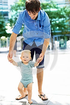 Baby taking first steps with fathers help