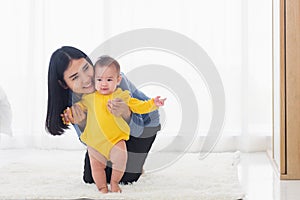 Baby taking first steps learning to walk with mother