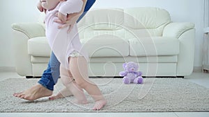 Baby taking first steps with mother`s help at home