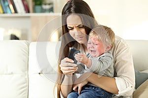 Baby tantrum fighting with his mother for a smart phone photo