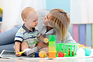 Baby with teacher playing with educational toys in nursery
