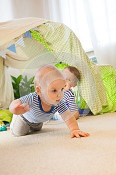 Baby toddler crawling on the carpet on the background of a children`s tent