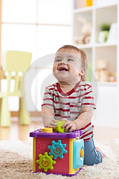 Baby toddler playing indoors with sorter toy sitting on soft carpet photo