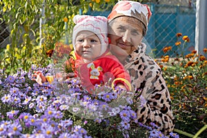 Baby together and grandmother in the flower garden