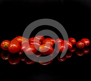 Baby tomatoes,cherry tomatoes and water drop on black background with reflection