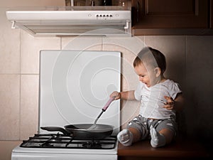 Baby toodler preparing dinner at the kitchen in the frying pan dark rich warm