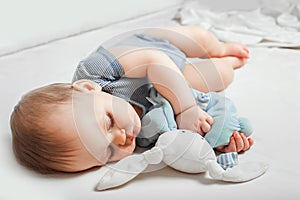 Baby with toy in hands sleeps on bed. Infant development concept, toddler restful sleep, teething, colic