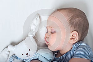 Baby with toy in hands sleeps on bed. Infant development concept, toddler restful sleep, teething, colic