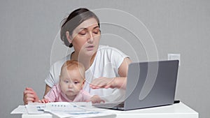 Baby tries to get attention from mother working on laptop