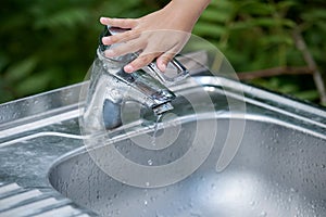 Baby try to turn off water faucet but water still leak. A child`s hand turning off the tap. Save water. World Water Monitoring Da