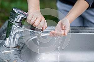 Baby try to turn off water faucet but water still leak. A child`s hand turning off the tap. Save water. World Water Monitoring Da