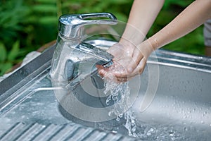 Baby try to turn off water faucet but water still leak. A child`s hand turning off the tap. Save water. World Water Monitoring Da