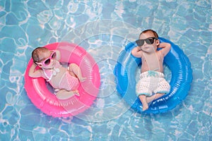 Baby Twin Boy and Girl Floating on Swim Rings