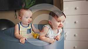 Baby twins play in a dry ball pool. Happy family kid dream concept. Baby smiling play in dry pool at home indoors two