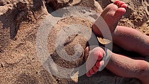 baby two feet on the sandy beach. Vertical video format