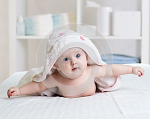 Baby under towel in bedroom after bath or shower. Textile and bedding for children.