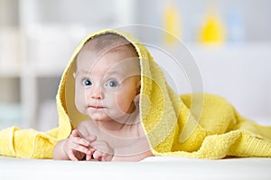 Baby under towel in bedroom after bath or shower. Textile and bedding for children.