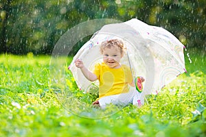 Baby under umbrella in summer rain