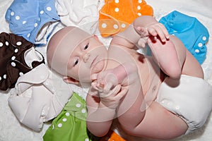 Baby Wearing a Cloth Diaper Surrounded by a Rainbow of Cloth Diapers photo