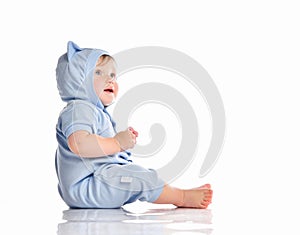 Baby wearing funny blue suit sit on studio floor