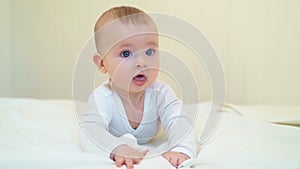 Baby in white lying on paunch on white bed