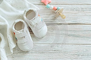 Baby white shoes and warm blanket on wooden background