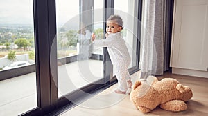 A baby by window, learning and walking for child development. Baby girl, toddler and young kid standing with support to