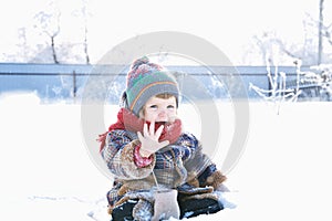 Baby in winter clothes outdoor remove her mittens and say hello. cute child in cap,scarf and mittens