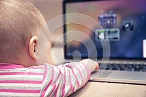 Baby working on laptop computer with hand reaching to touchpad