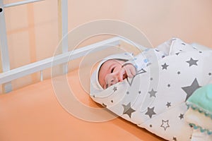 Baby wrapped in a blanket. Sleeping Cute Newborn Infant Wrapped in Baby Blanket in Acrylic Hospital Bassinet just after Birth