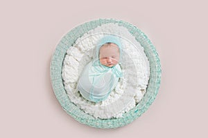 Baby wrapped in blue blanket in basket, topview