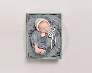 Baby wrapped in gray blanket resting, topshot