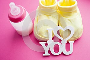 Baby yellow booties. Children's shoes and toys on pink background. Newborn.