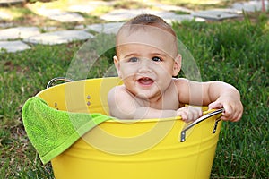 Baby in yellow bucket in garden