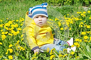 Baby in yellow jacket among dandelions