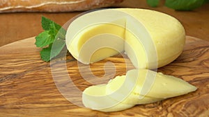 Babybel cheese head on the rustic table with sliced pieces