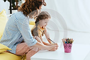 Babysitter and cute kid drawing with