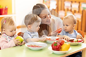 Babysitter feeding nursery babies. Toddlers eat healthy food in daycare