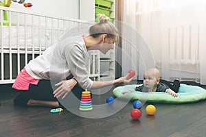 Babysitting - nanny playing with little baby on the floor