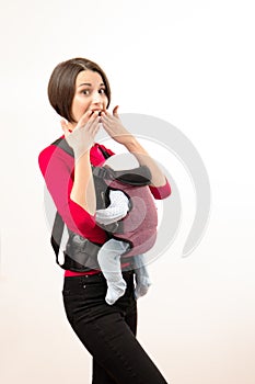 Babywearing attractive young mother with baby in wrong carrier. Isolated on white