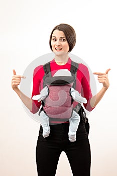 Babywearing confused young mother with baby in not ergonomic sling. Isolated on white