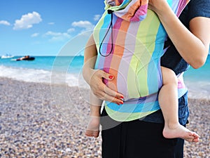 Babywearing practice with mother carrying baby in SSC soft structured carrier on seaside
