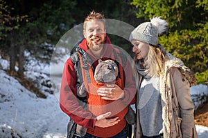 Babywearing winter forest walk with family and their baby son in ergonomic carrier