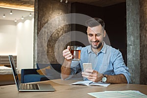 Bachelor man daily routine working from home single lifestyle concept drinking tea browsing smartphone